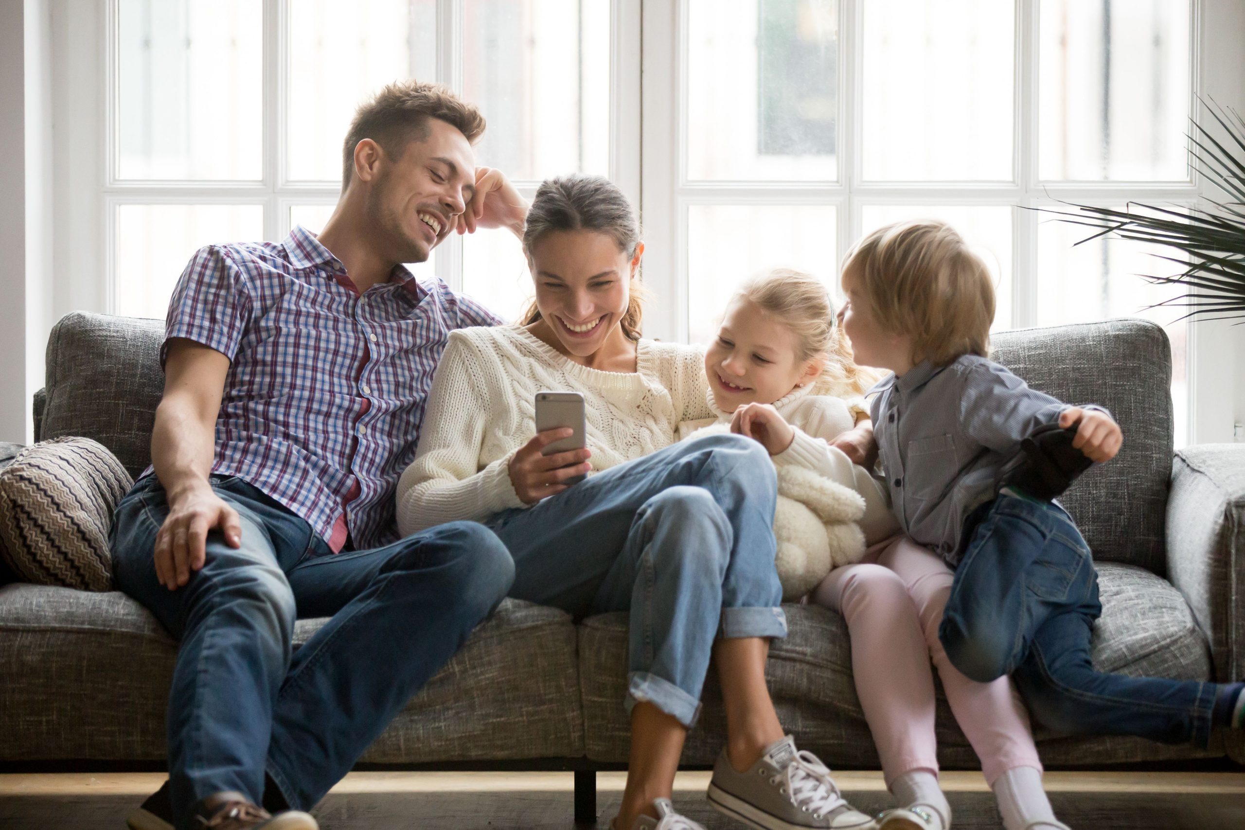 Familie schaut sich auf dem Sofa eine Budgetplaner-App an und spricht über Geld.