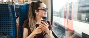 Frau reist im Zug und hört Musik
